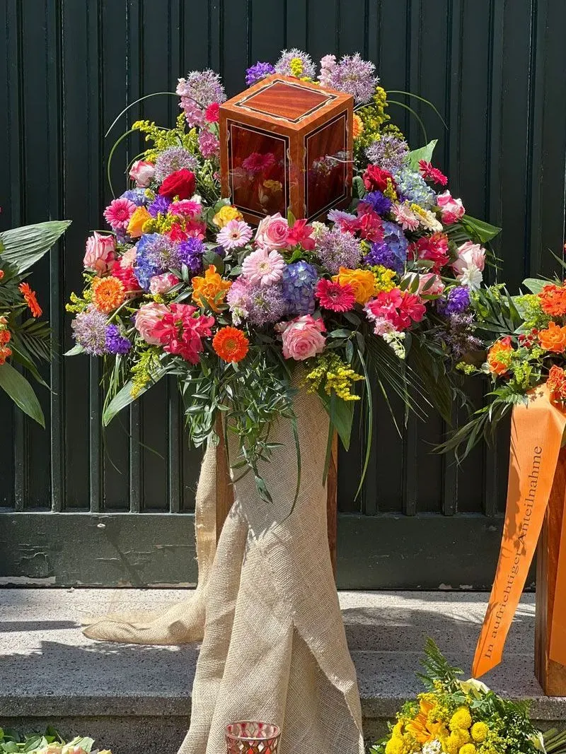 Baumbestattung Urne mit Rose aufgebahrt auf bunten Blumenstrauss Bestattungshaus LESCH Hannover