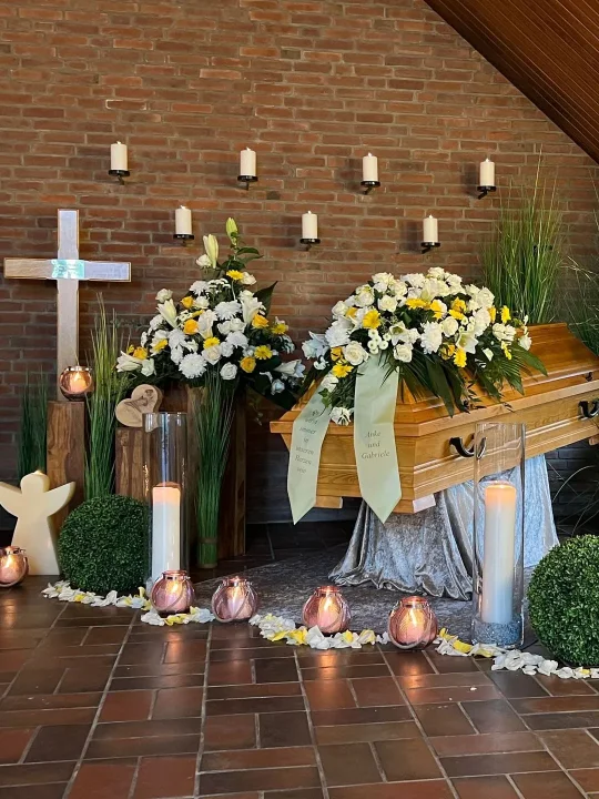 Sarg geschmueckt mit gelben und weissen Blumen